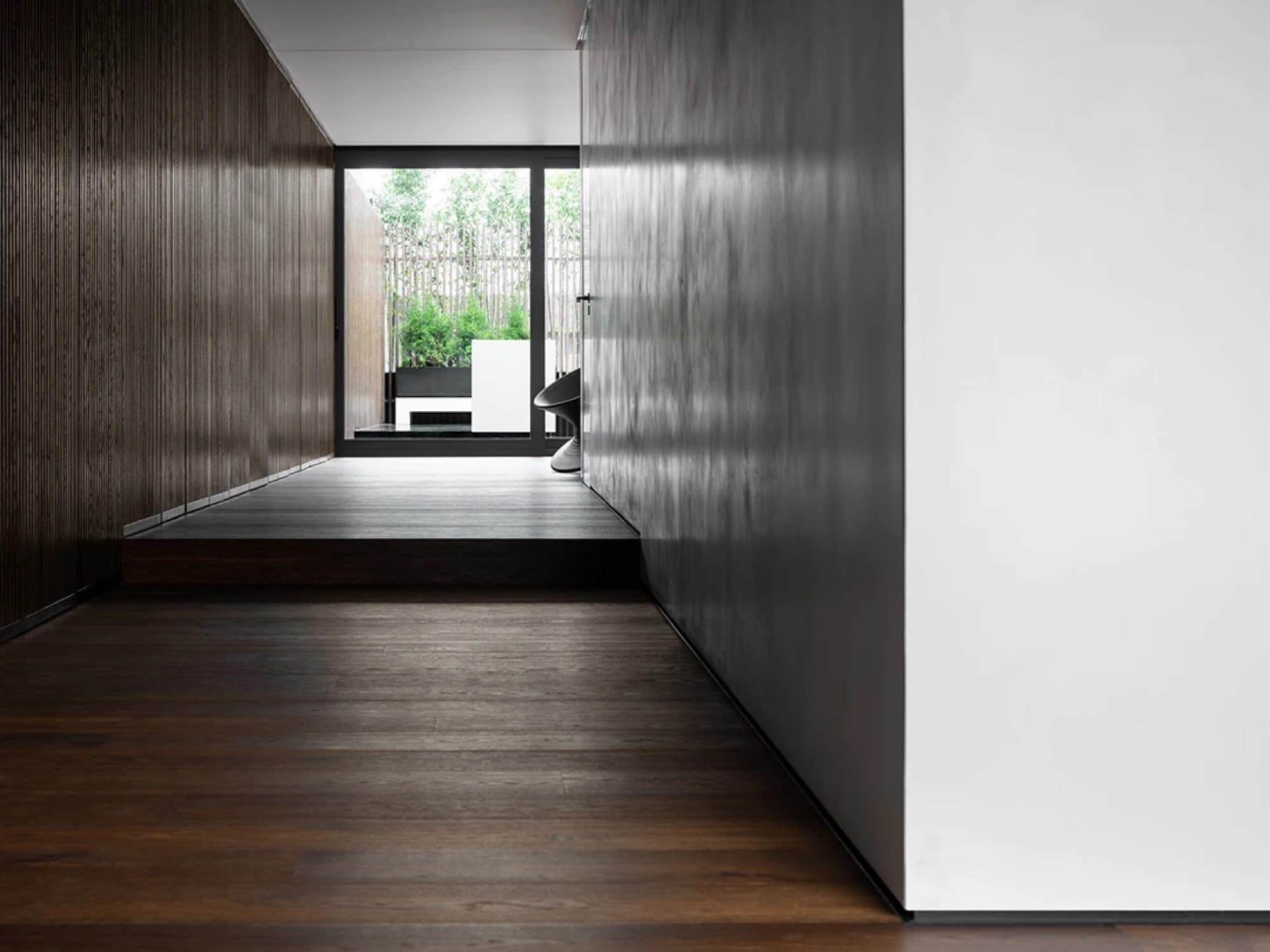 Corridoio con boiserie in legno scuro e parete bianca rasata