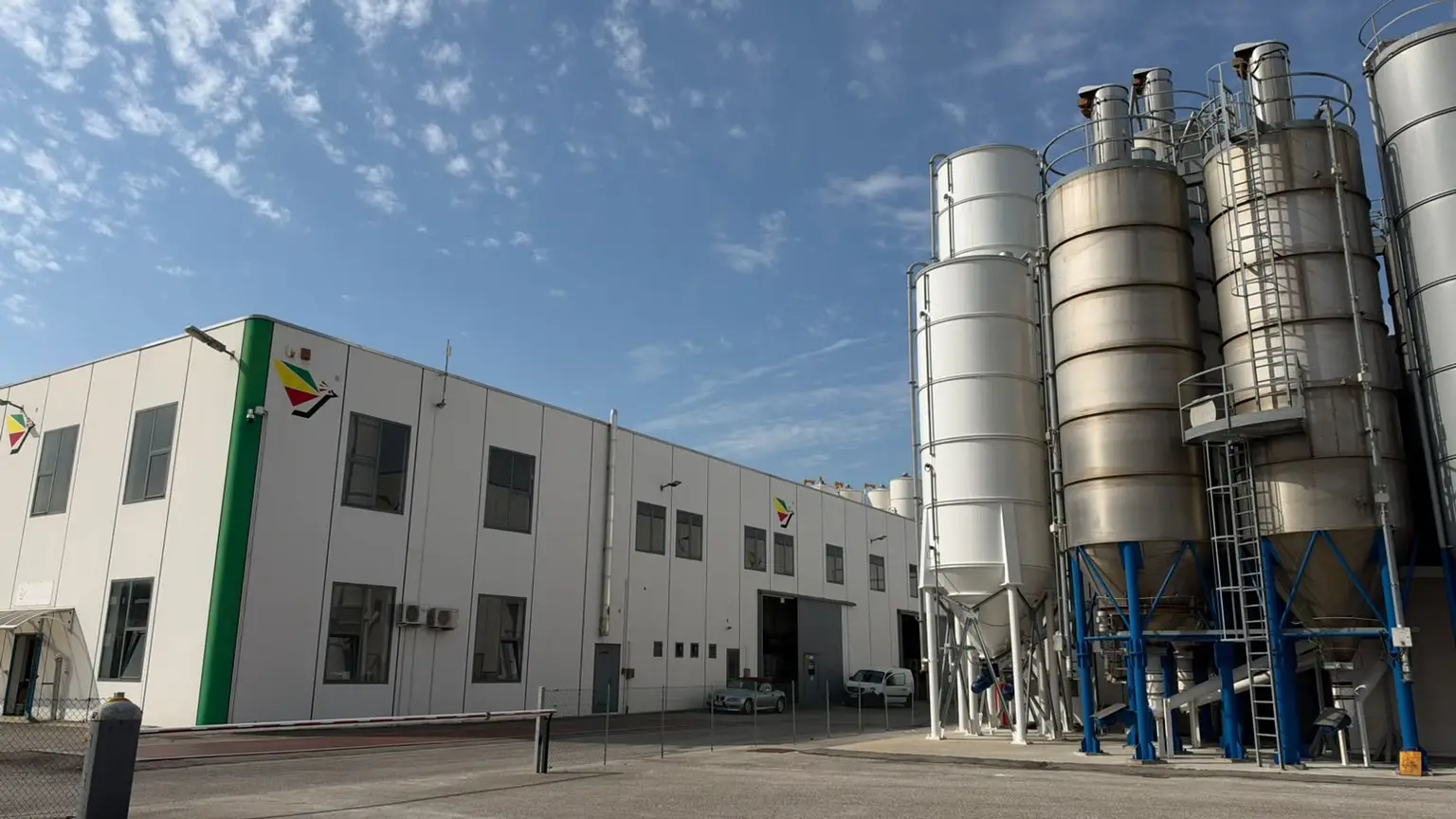 Lo stabilimento Colorificio Gottardo sotto il cielo azzurro, con il capannone e i silos delle materie prime